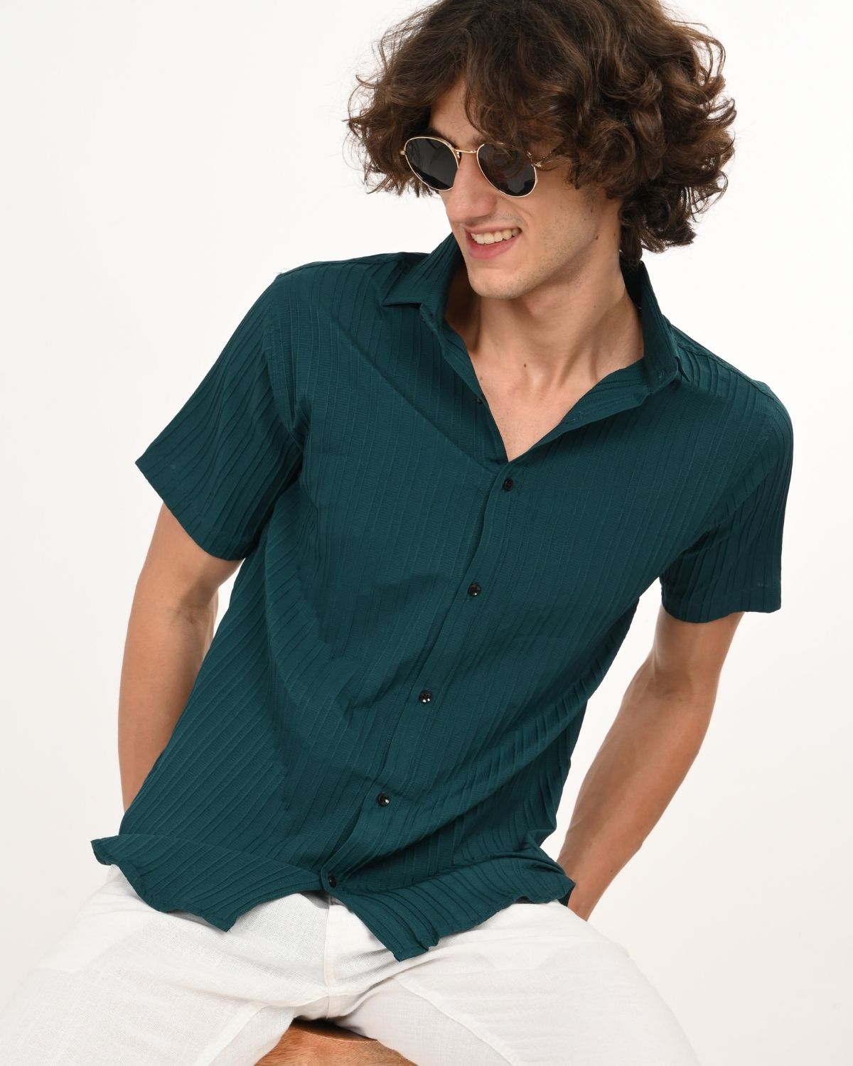 Model sitting sideways wearing teal green textured men’s shirt