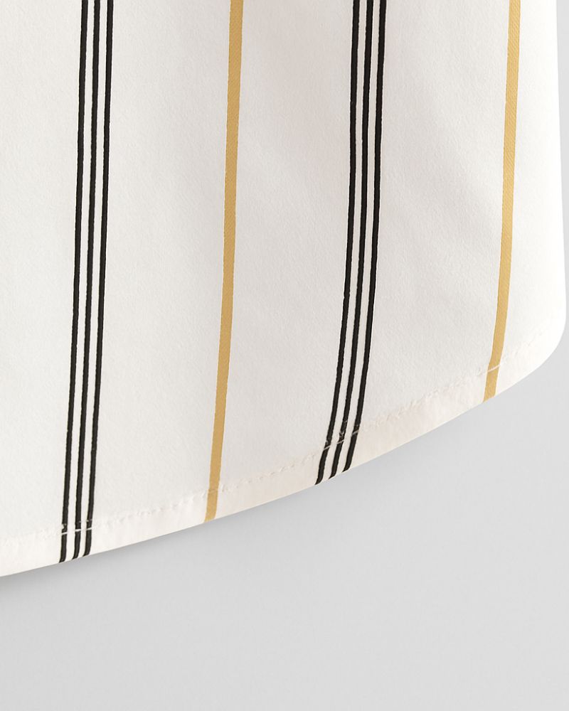 Close-up of curved hem on men’s vertical striped shirt in beige and black, showing neat stitching on lightweight white fabric