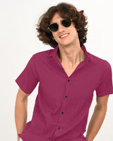 Close-up smiling man in magenta shirt with sunglasses.