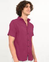 Man in magenta textured short-sleeve shirt side view.