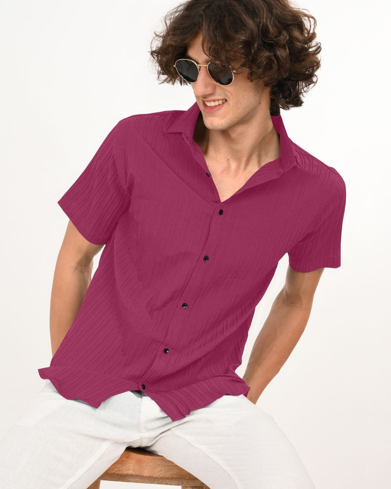 Man leaning forward in magenta shirt and sunglasses.