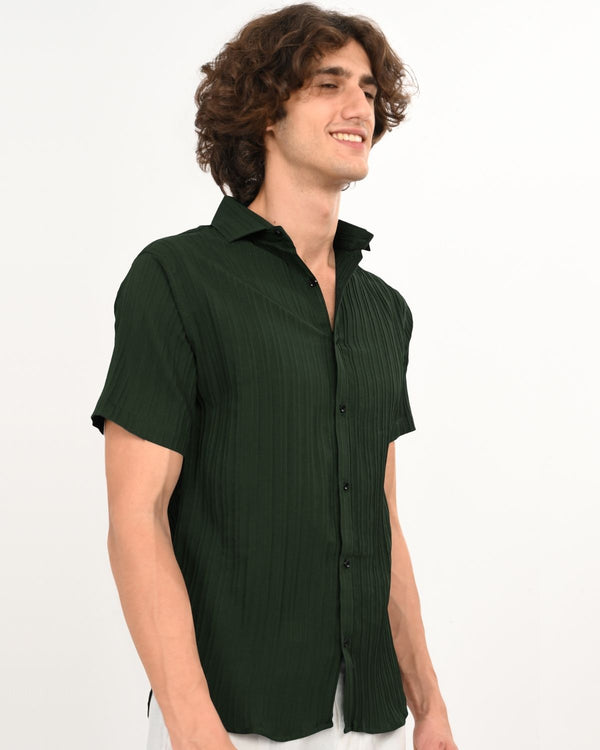 Man wearing a dark green textured short-sleeve shirt, side pose with a smile.