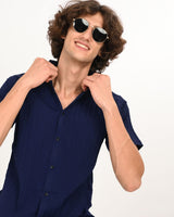 Model adjusting collar wearing navy blue textured short-sleeve shirt