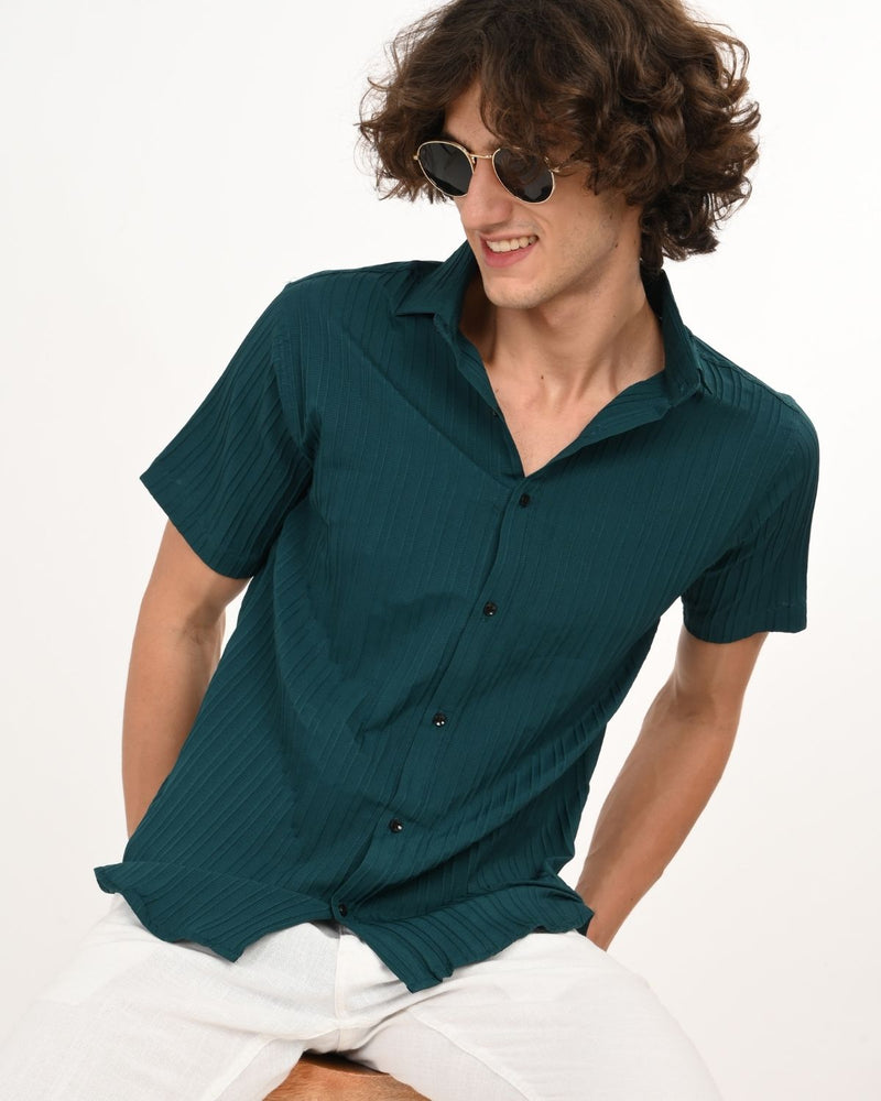Model sitting sideways wearing teal green textured men’s shirt