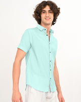 Side angle of model wearing mint green textured short-sleeve shirt