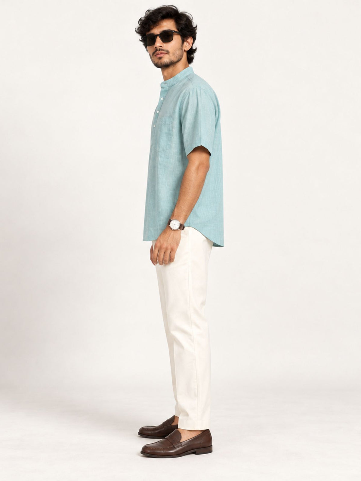 Side view of Aavir seafoam blue kurta shirt styled with ivory trousers and brown loafers.