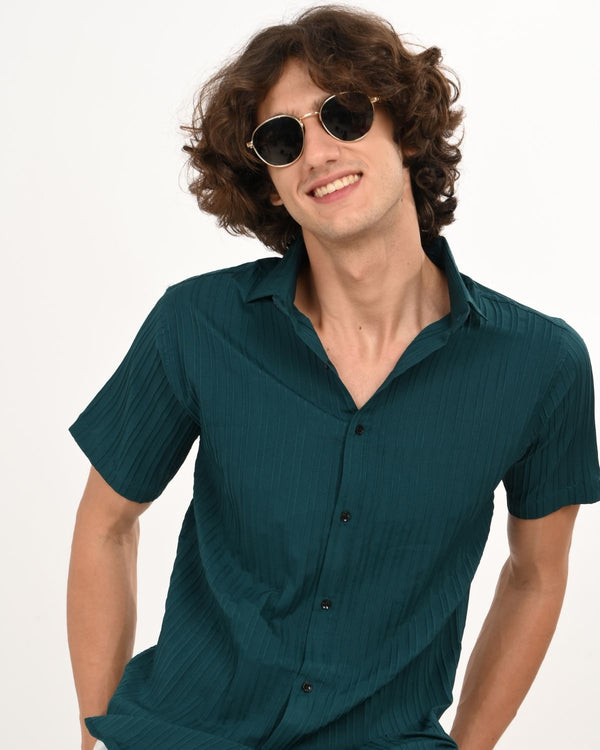 Smiling model in teal green textured short-sleeve shirt with shades